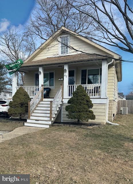 bungalow-style home with central air condition unit, fence, and a porch