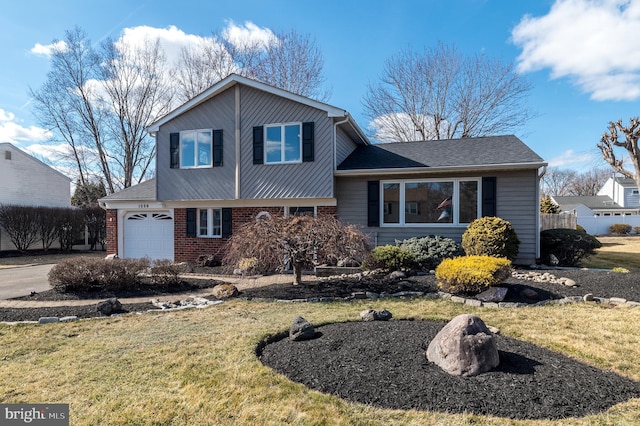 split level home featuring brick siding, a front yard, fence, a garage, and driveway