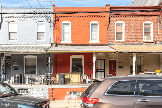 multi unit property featuring a porch, cooling unit, and brick siding