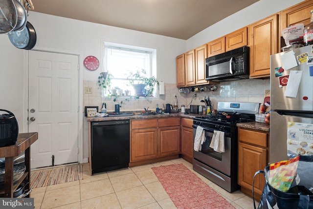 kitchen with brown cabinetry, light tile patterned flooring, decorative backsplash, and black appliances