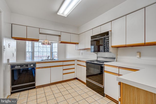 kitchen featuring light countertops, a sink, black appliances, and white cabinetry