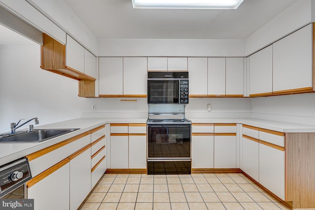 kitchen with white cabinets, black appliances, light countertops, and a sink