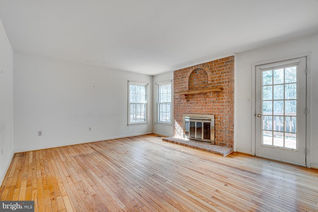 unfurnished living room with a brick fireplace, baseboards, and hardwood / wood-style flooring