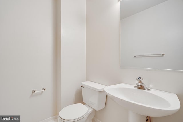 bathroom with a sink, toilet, and baseboards