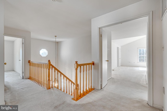 corridor featuring carpet flooring, vaulted ceiling, and an upstairs landing