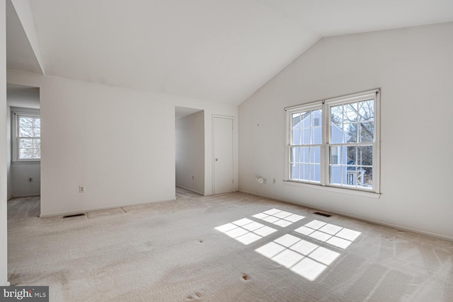 unfurnished room with lofted ceiling, carpet flooring, and visible vents