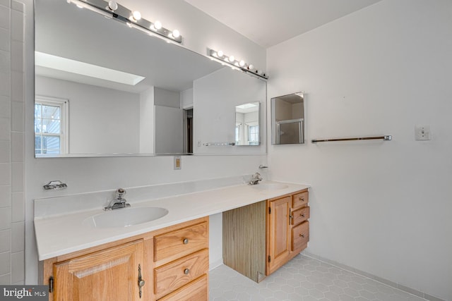 bathroom featuring a skylight, tile patterned floors, a sink, and double vanity