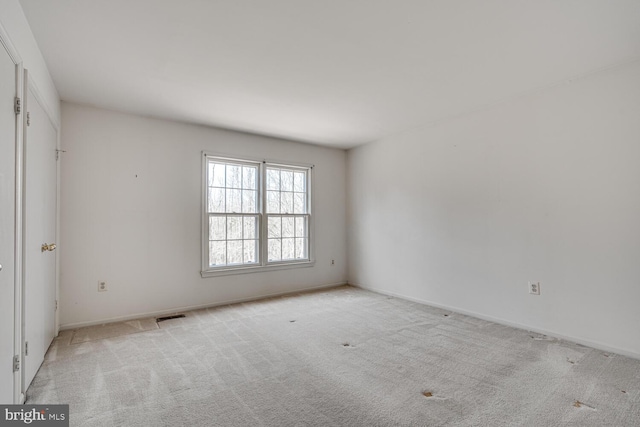 spare room with baseboards, visible vents, and light colored carpet