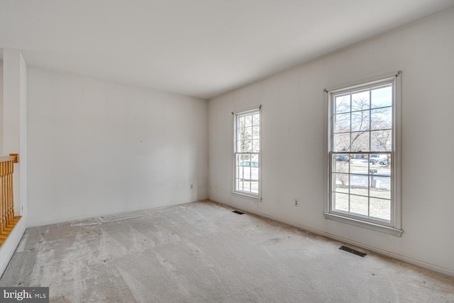 carpeted empty room featuring visible vents