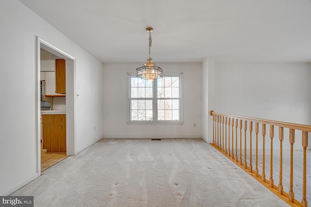 unfurnished dining area featuring a notable chandelier, baseboards, and carpet flooring