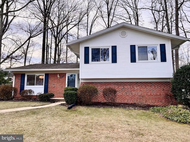 tri-level home with brick siding and a front lawn