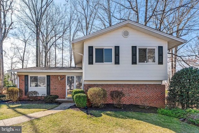 split level home featuring a front yard and brick siding