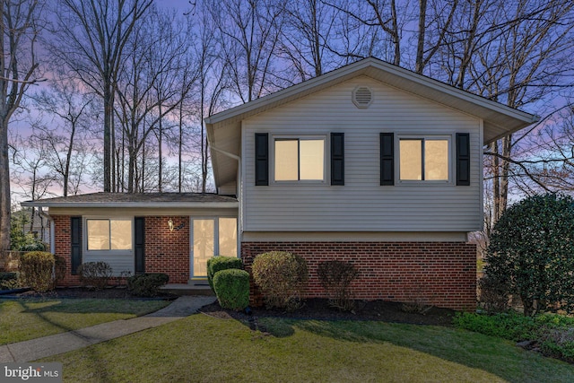 tri-level home with brick siding and a front lawn