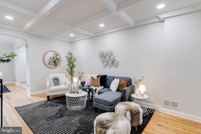 living area with light wood-type flooring, visible vents, arched walkways, and beam ceiling