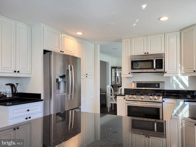 kitchen featuring white cabinetry, dark stone counters, stainless steel appliances, and recessed lighting