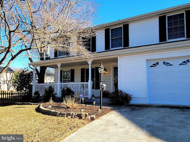 traditional home featuring driveway, covered porch, fence, and a front yard