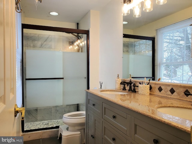 bathroom featuring double vanity, a stall shower, a sink, and toilet