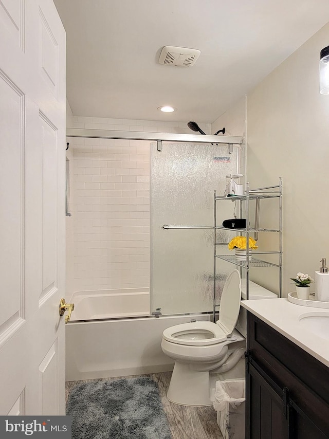 full bath with visible vents, vanity, toilet, and bath / shower combo with glass door