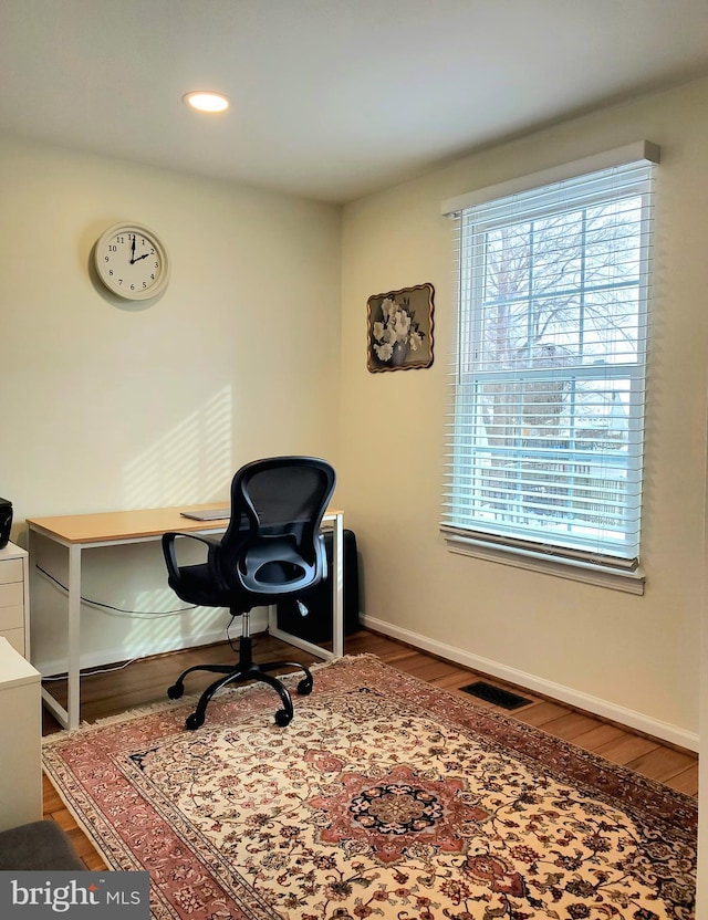 office space featuring wood finished floors, visible vents, and baseboards