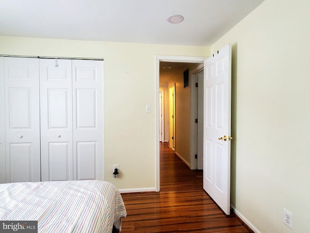 bedroom with dark wood-style floors, a closet, and baseboards