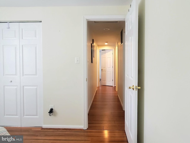 hallway featuring baseboards and wood finished floors