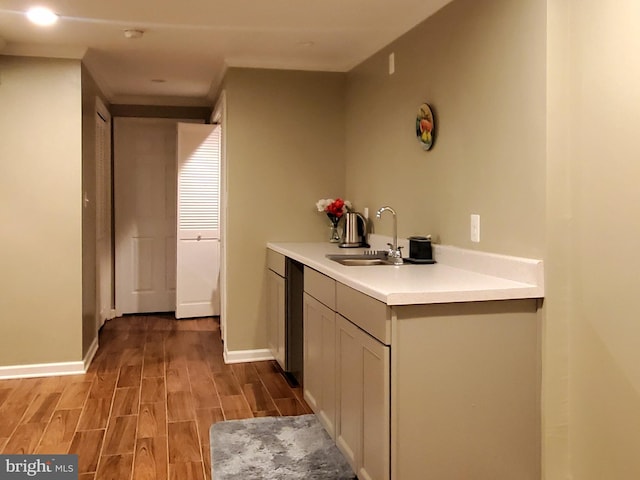 kitchen featuring baseboards, light countertops, a sink, and wood tiled floor