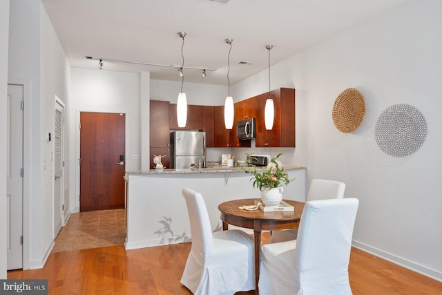 dining room featuring light wood-type flooring, baseboards, and track lighting