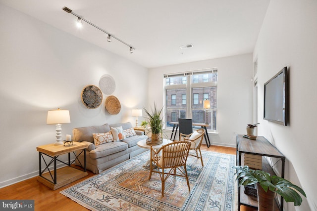 living room featuring baseboards, visible vents, and wood finished floors