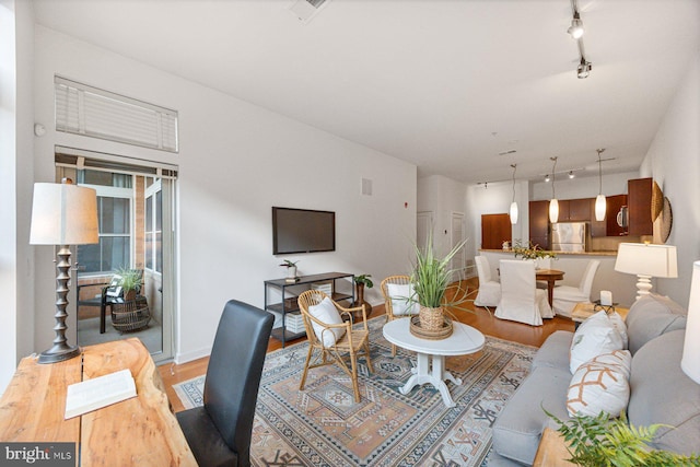 living room with visible vents, track lighting, baseboards, and wood finished floors