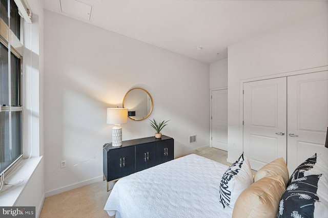 bedroom with light carpet, visible vents, baseboards, a closet, and attic access