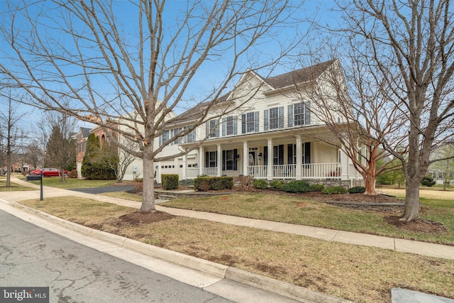 view of front facade with a garage, a front yard, covered porch, and driveway