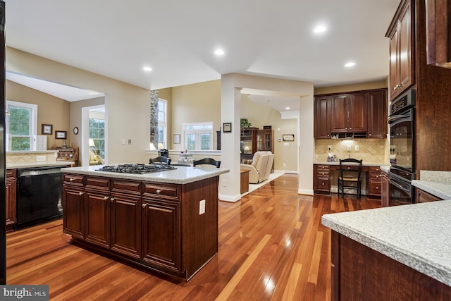 kitchen with backsplash, black appliances, wood finished floors, and light countertops