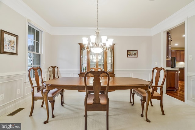 dining area featuring visible vents, a notable chandelier, crown molding, and a decorative wall