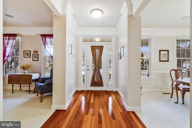 foyer with crown molding and wood finished floors