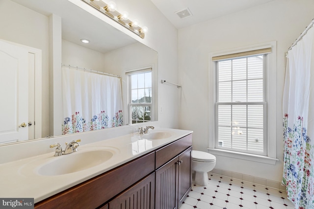 full bath with double vanity, visible vents, toilet, and a sink