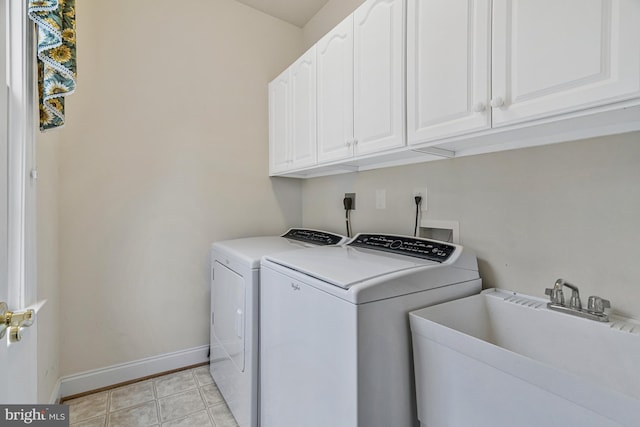 washroom featuring a sink, baseboards, cabinet space, and separate washer and dryer