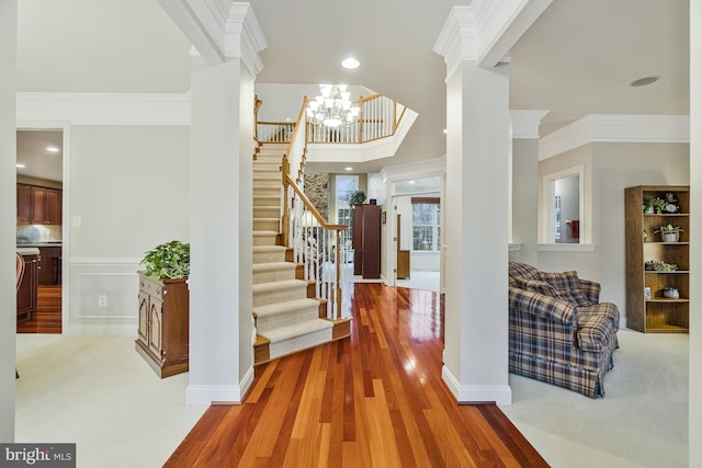 foyer with a chandelier, stairway, wood finished floors, and ornamental molding