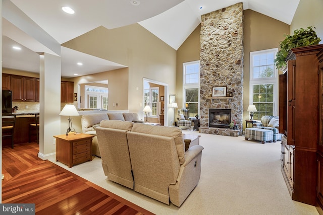 living room featuring a wealth of natural light, high vaulted ceiling, light wood-style flooring, and a fireplace