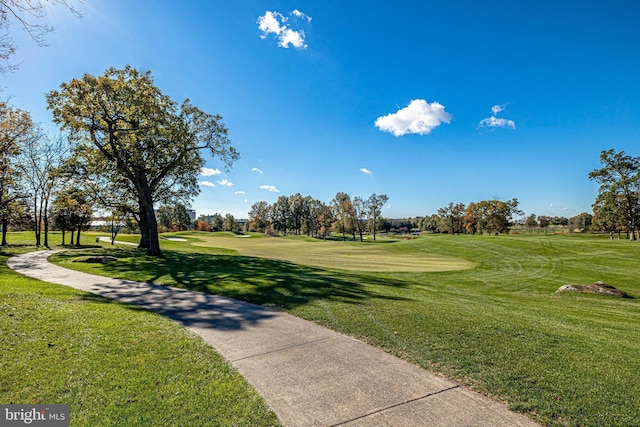 view of community featuring view of golf course and a yard