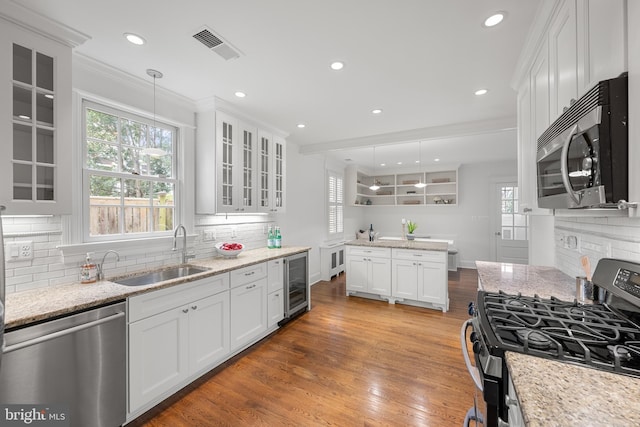 kitchen with stainless steel appliances, visible vents, a sink, light wood-type flooring, and beverage cooler