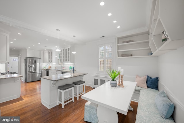 kitchen featuring stainless steel appliances, glass insert cabinets, white cabinetry, a peninsula, and a kitchen bar