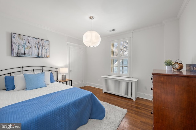 bedroom with wood finished floors, visible vents, baseboards, radiator, and crown molding