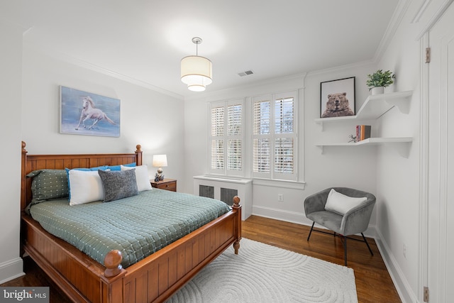 bedroom with baseboards, wood finished floors, visible vents, and crown molding