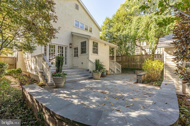 back of property featuring entry steps, a patio area, fence, and stucco siding