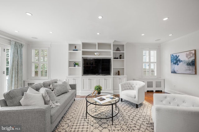 living area featuring light wood-type flooring, a healthy amount of sunlight, crown molding, and recessed lighting