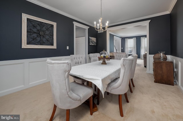 dining room featuring wainscoting, crown molding, a notable chandelier, and light colored carpet