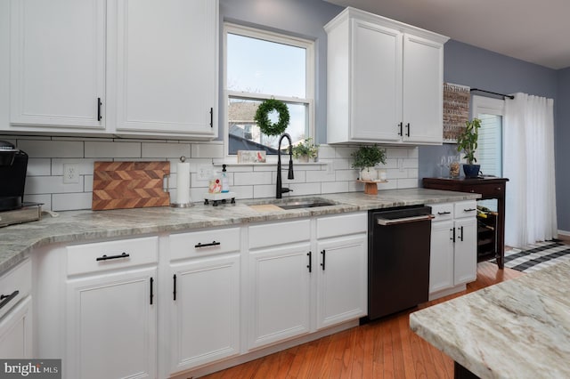 kitchen with dishwashing machine, a sink, white cabinetry, light wood-style floors, and decorative backsplash