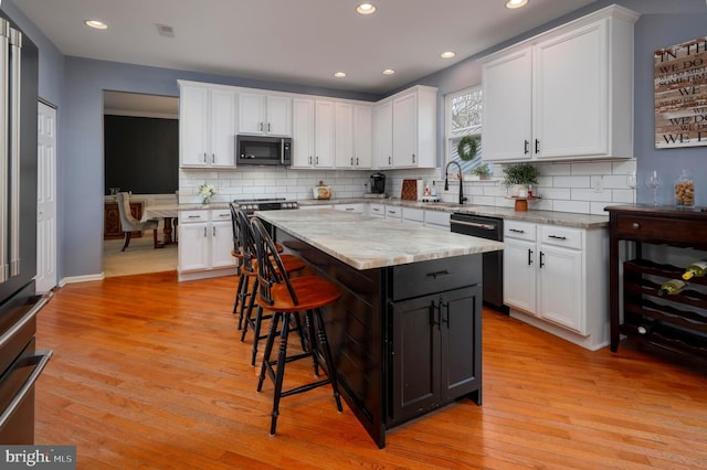 kitchen featuring light wood-style floors, white cabinetry, stainless steel appliances, and a breakfast bar area