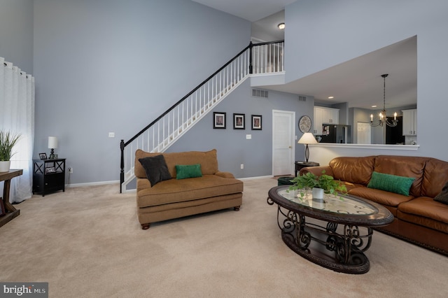 living area featuring light colored carpet, stairway, a towering ceiling, an inviting chandelier, and baseboards