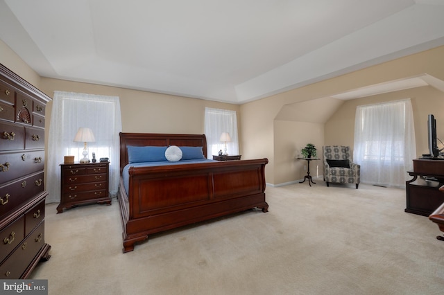 bedroom featuring a raised ceiling, light colored carpet, baseboards, and multiple windows